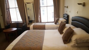 Una camera d'albergo con due letti, un tavolino e una sedia.