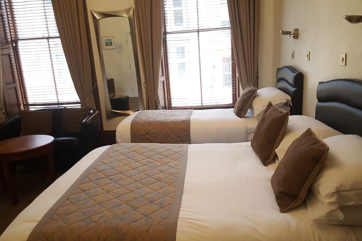 A hotel room with two beds, a small table, and a chair.