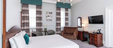 Una habitación de hotel con una cama grande, un escritorio con una silla, un televisor y una ventana con cortinas.