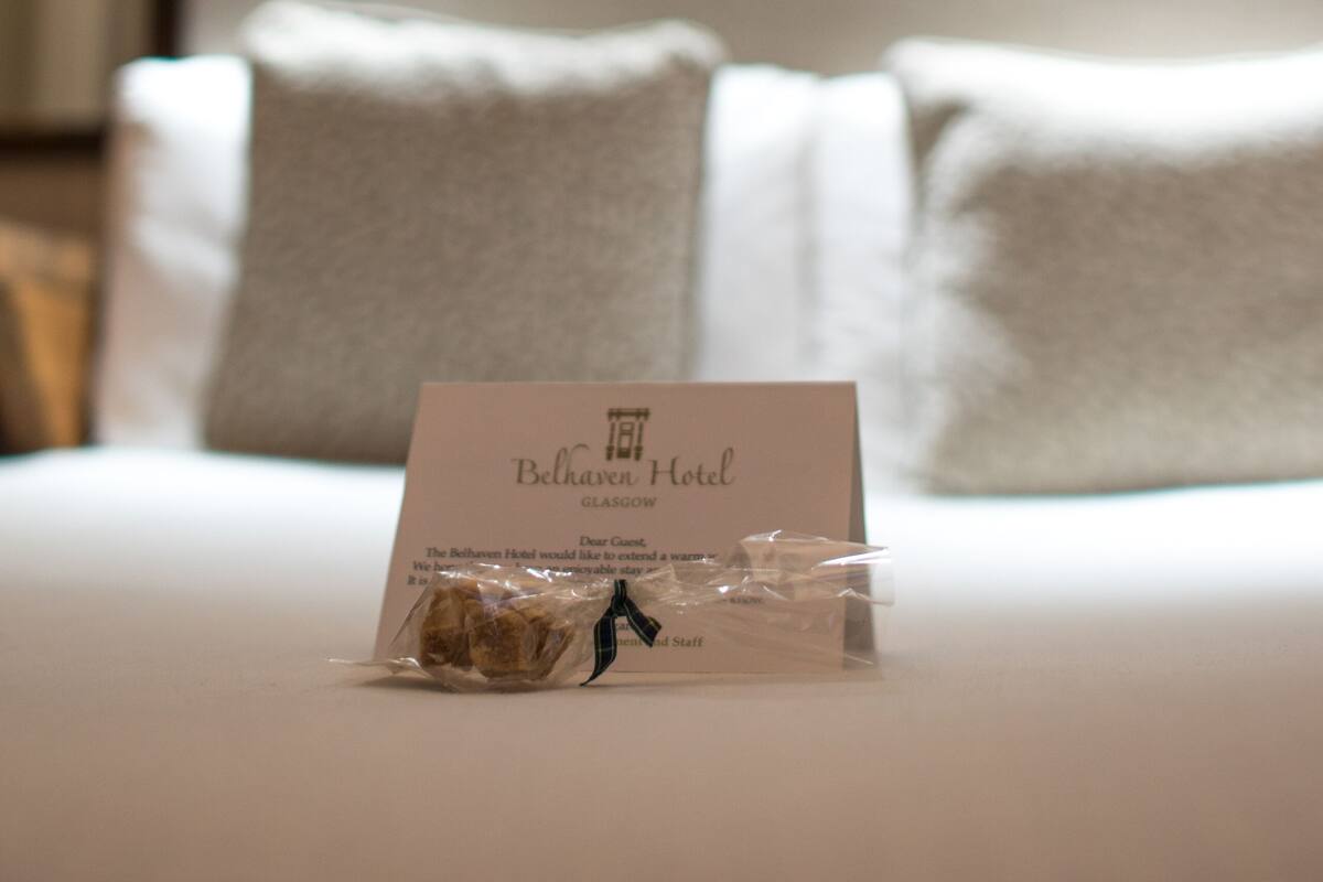 A neatly made bed with a card on it, a pillow, and a headboard.