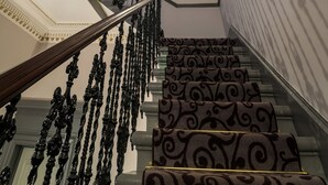 Un magnifique escalier avec des rampes richement décorées et un plafond orné.
