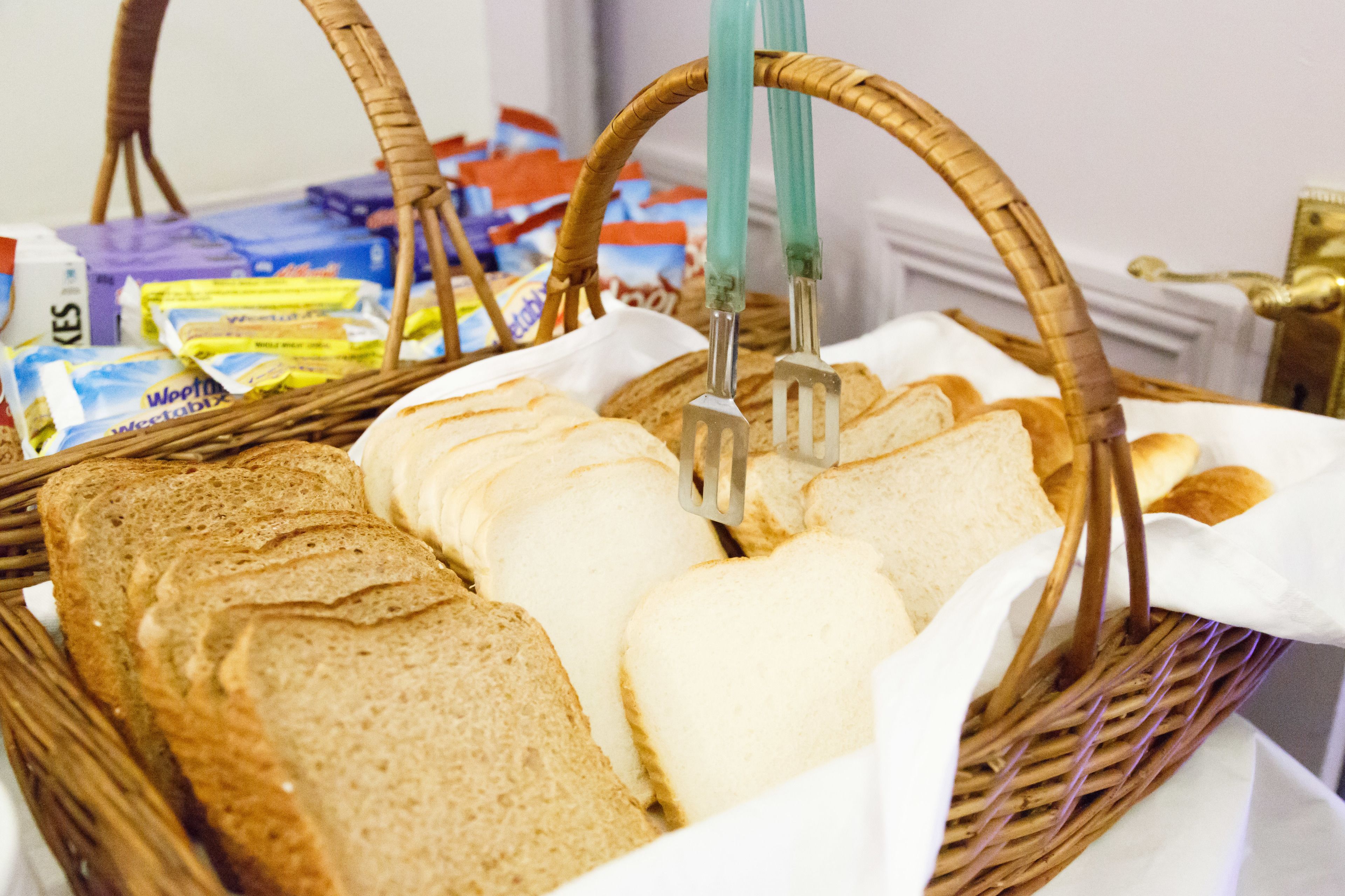 A wicker basket containing various breads and a knife.