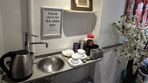 Ett hotellbadrum med handfat, vattenkokare och en plats för te. Det finns en skylt som ber gästerna att hålla tehörnan snygg och städad.