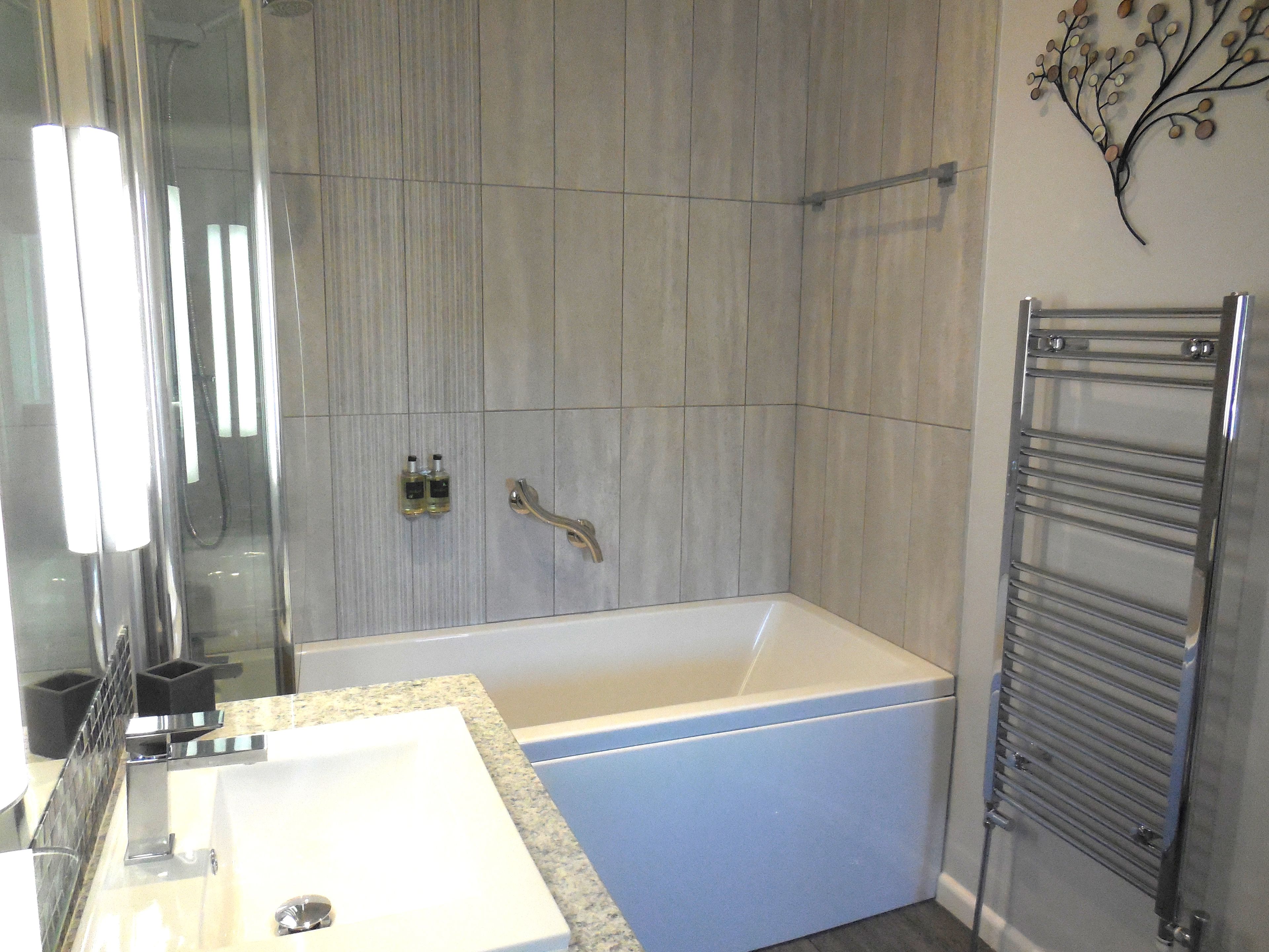 Une salle de bain moderne avec une grande baignoire, un lavabo et une douche à l’italienne.