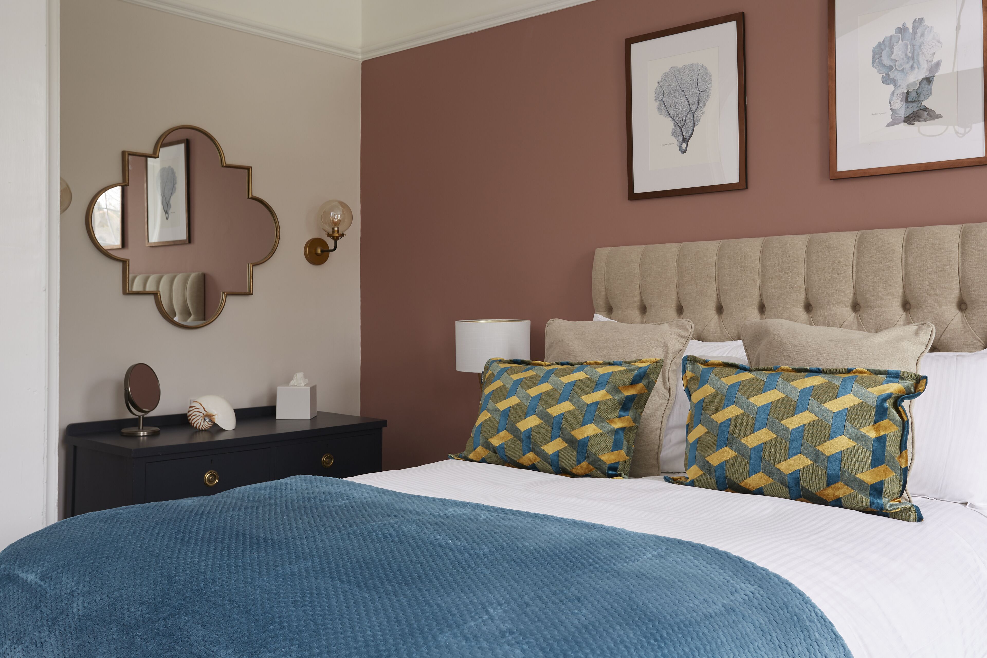 Un dormitorio ordenado con cama, mesitas de noche y decoración en la pared.
