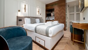 A modern hotel room with a large bed, a desk, and a seating area. - Fitzroy (London)