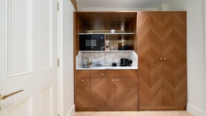 A compact kitchen with a built-in oven, a coffee maker, and a microwave. - Fitzroy (London)
