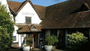 A building with a reception area, a pitched roof, and large potted plants. - The Roebuck Inn (Stevenage)