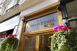The Craven Hotel sign with a large entrance and hanging flower baskets. - The Craven Hotel (London)