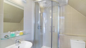 A modern bathroom with a glass-enclosed shower, a white sink, and a toilet. - The Craven Hotel (London)