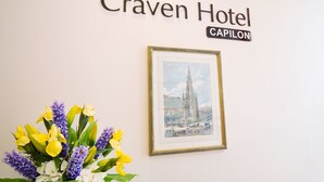A framed artwork of a cathedral, a sign for Craven Hotel Capilon, and a bouquet of flowers. - The Craven Hotel (London)