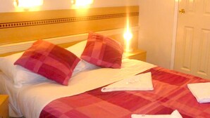 Ein Hotelzimmer mit einem Bett, zwei Kissen, einem Nachttisch und einer Nachttischlampe.