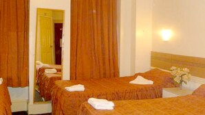 Ein Hotelzimmer mit zwei Betten, einem Spiegel, einem Nachttisch mit Blumenvase und einer Wandleuchte.
