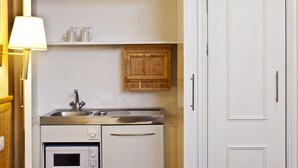 Eine kompakte Küche mit integriertem Mikrowellenherd, einer Edelstahl-Spüle und einem Holzkasten über der Arbeitsplatte.