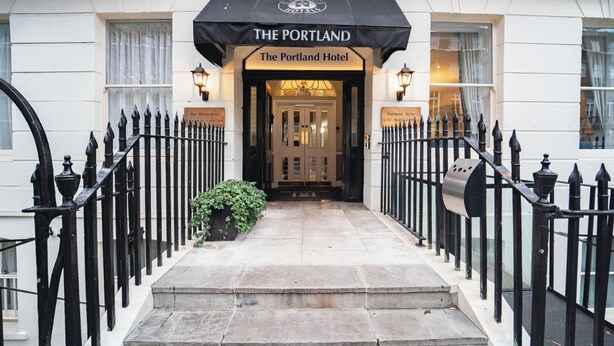 Der Eingang zum The Portland Hotel mit einer schwarzen Markise, Steinstufen und schwarzen Eisengeländern.