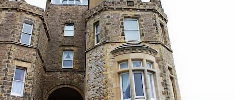Un edificio histórico de piedra con una torre destacada y una entrada abovedada.