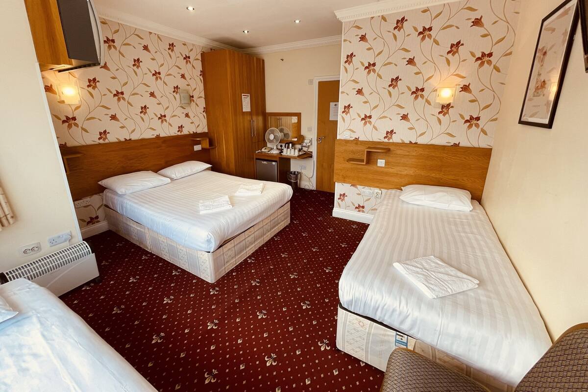 Habitación cuádruple Deluxe, varias camas | Caja de seguridad en la habitación y ropa de cama