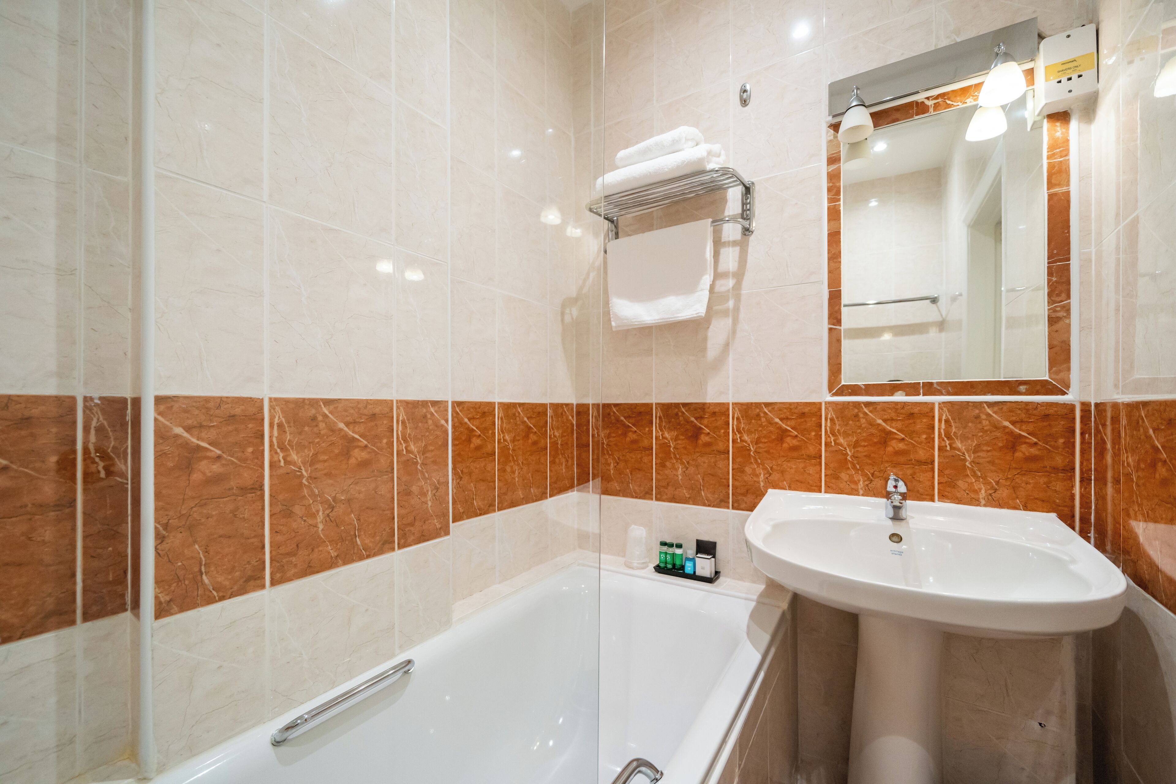 Un baño moderno con ducha envuelta en vidrio, un lavabo blanco y un espejo sobre él.