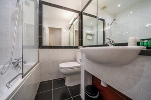 Une salle de bain moderne dotée d’une douche à parois de verre, de toilettes blanches et d’un grand lavabo avec un plan de travail en marbre.