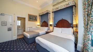 A hotel room with two beds, a bathroom, and a door leading to another room.