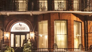 Un hotel de varios pisos con fachada de ladrillo clásico, ventanas amplias y una entrada destacada con un letrero.