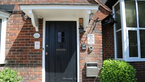 A brick house with a black door, a mailbox, and a sign on the wall. - Debden Guest House (Uxbridge)