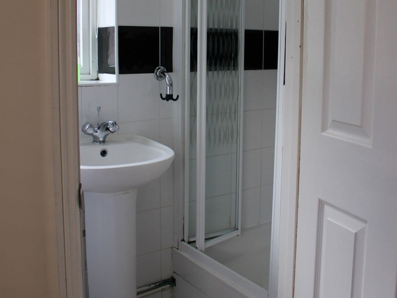 A bathroom with a white sink, a mirror, and a glass shower enclosure.