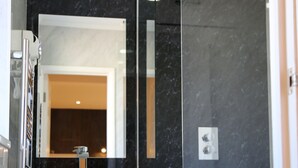 A modern bathroom with a white vanity, a large mirror, and a glass-enclosed shower area. - Debden Guest House (Uxbridge)