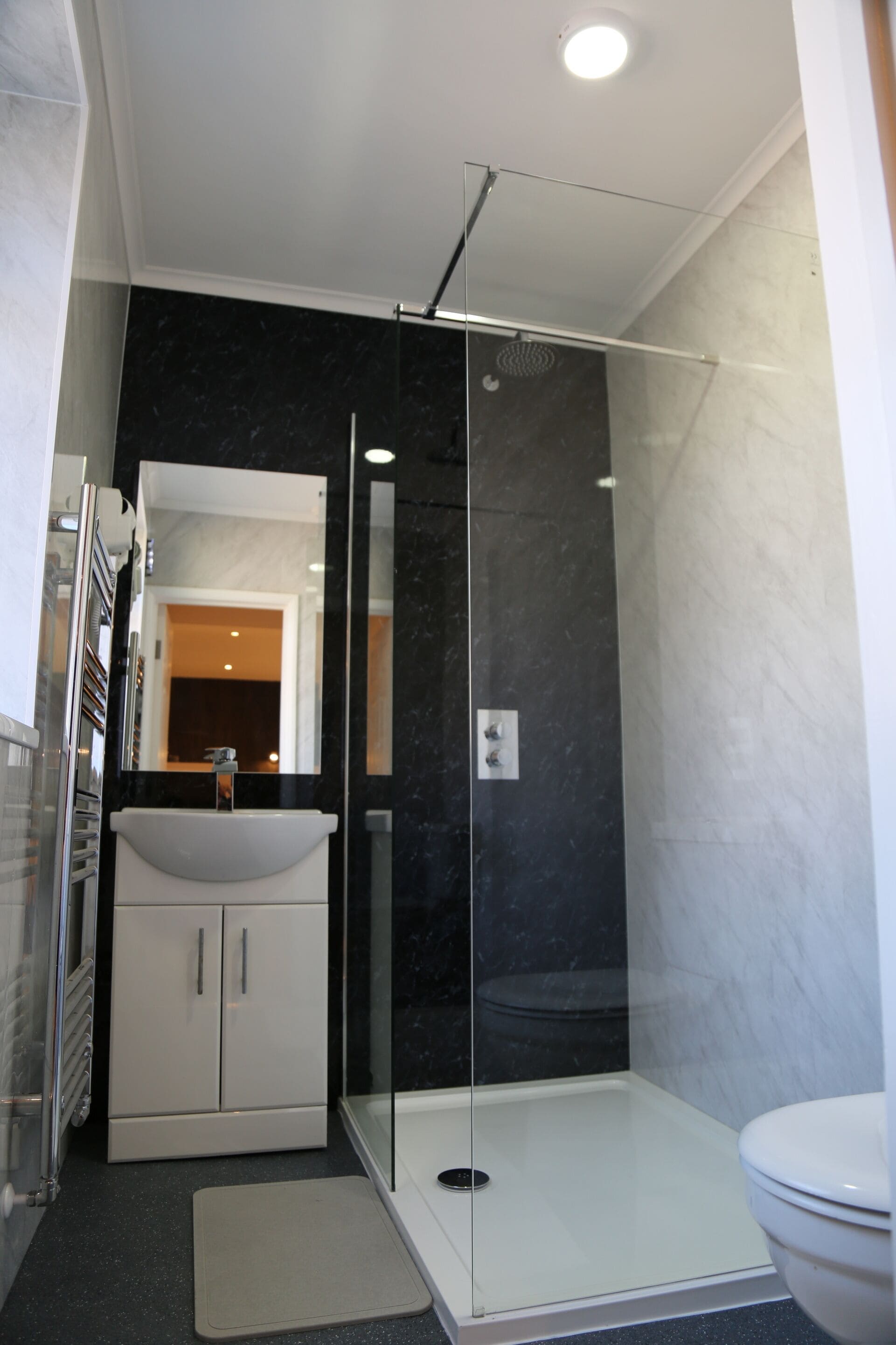 A modern bathroom with a glass-enclosed shower, a white sink, and a toilet.