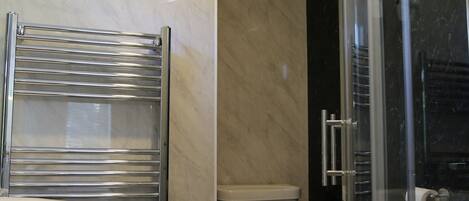 A modern bathroom with a glass shower enclosure, a chrome towel rack, and a toilet.