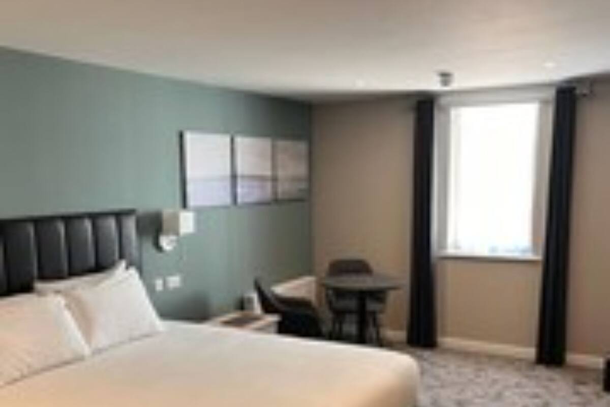 A hotel room with a large bed, a desk, and a chair.