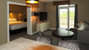 Una camera d'albergo con un letto, una TV, una scrivania, una sedia, un divano e un balcone con vista.