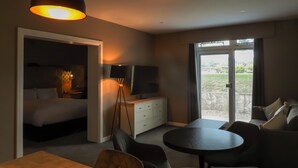 Camera d'albergo con un letto, una televisione, una scrivania, un tavolo da pranzo e un divano. Una porta scorrevole dà accesso a una zona esterna.
