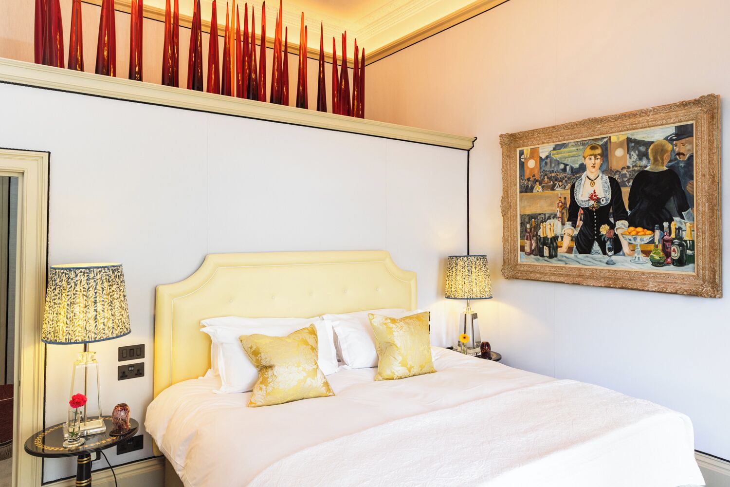 Ein Hotelzimmer mit einem Bett, zwei Nachttischen, einem Gemälde und einer dekorativen Decke.