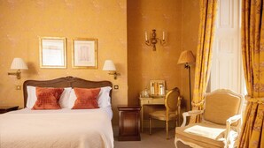 A hotel room with a bed, two framed pictures on the wall, a desk with a chair, and a lamp. - Dukes Bath (Bath)