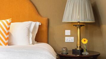 Une chambre d’hôtel comprenant un lit, une table de chevet avec une lampe, un vase et deux prises électriques.