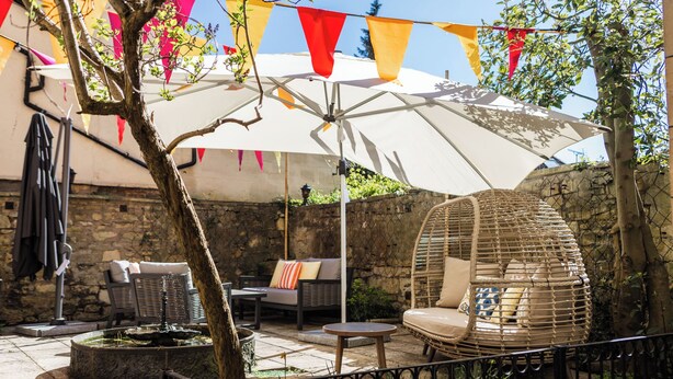 A patio with outdoor seating, a decorative umbrella, and a stone wall. - Dukes Bath (Bath)