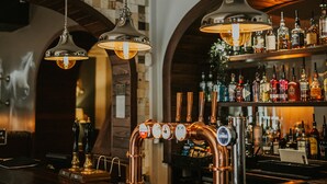 A bar area with copper faucets, hanging pendant lights, and a variety of liquor bottles on shelves. - The Croft Hotel (Darlington)