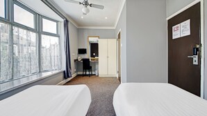 A hotel room with two beds, a desk, a chair, a television, and a wardrobe. - OYO Bostons Manor Hotel, Hanwell London (London)