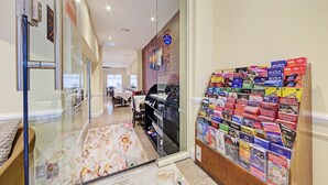 A hotel corridor with a dining area, a glass door, and a wall display of travel brochures. - OYO Bostons Manor Hotel, Hanwell London (London)