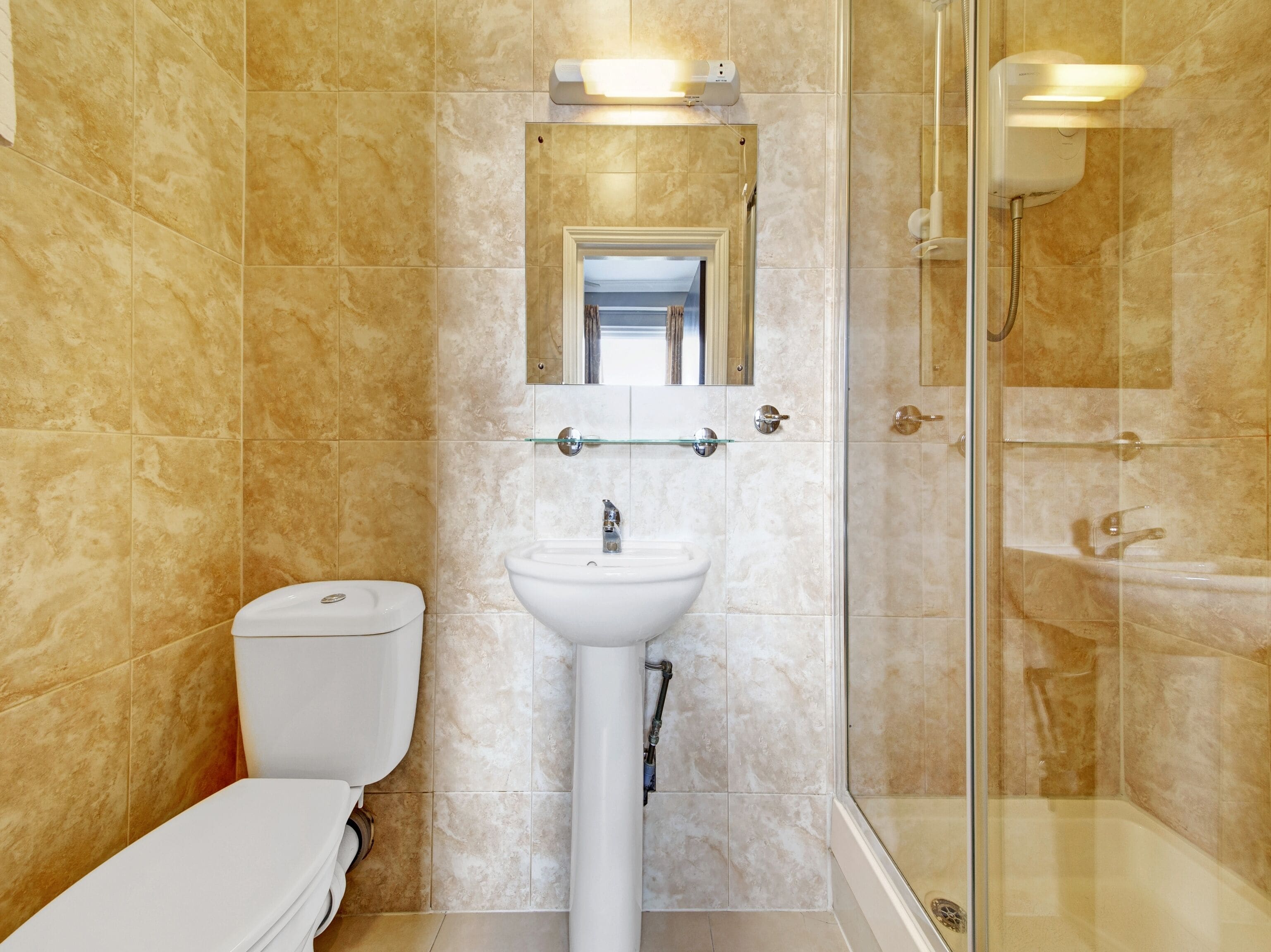 A bathroom with a toilet, sink, and glass shower enclosure.