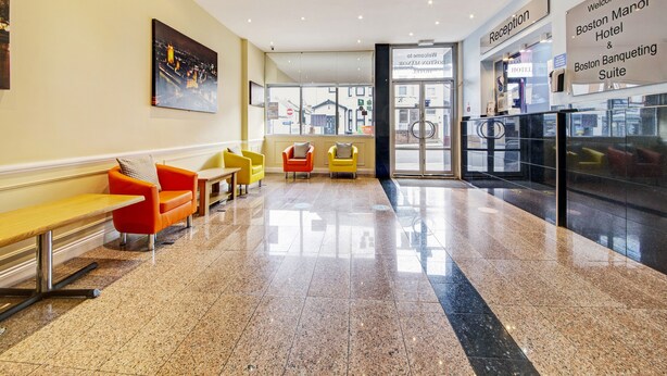 A hotel reception area with a modern design, featuring a reception desk, seating area with chairs, and a glass door entrance. - OYO Bostons Manor Hotel, Hanwell London (London)