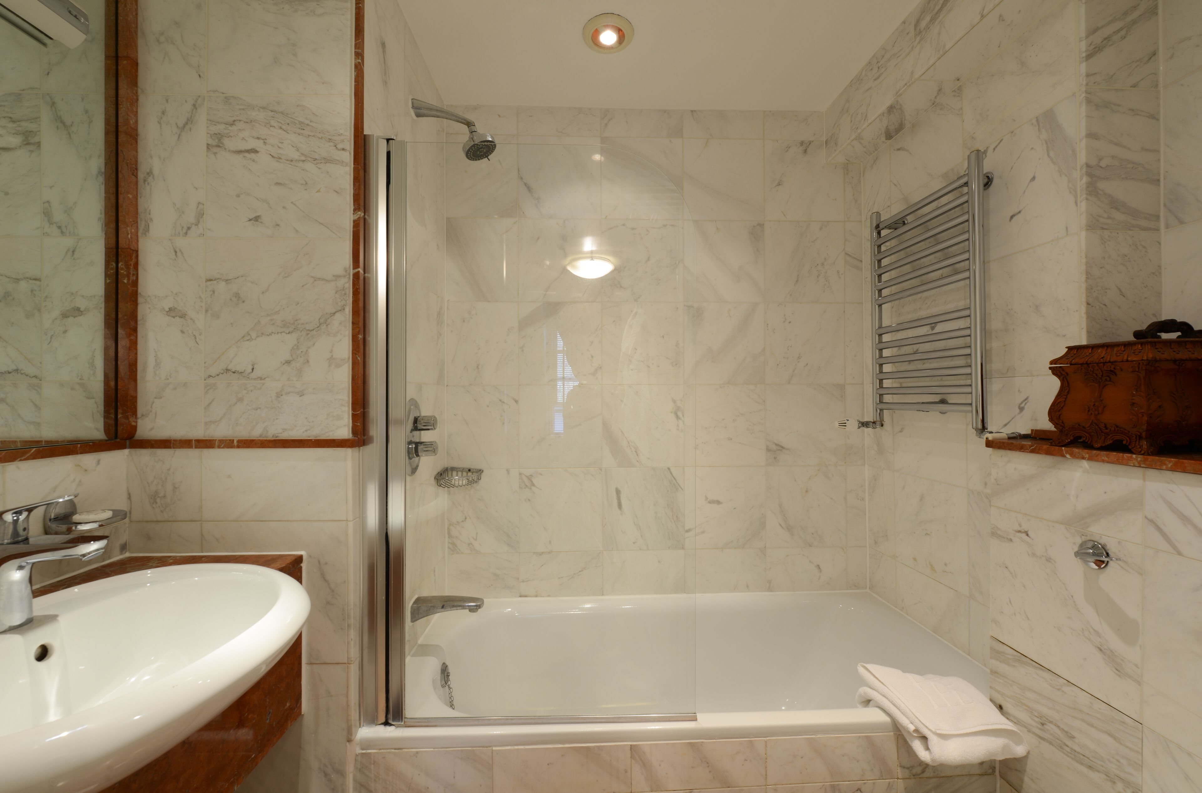 A bathroom with a glass-enclosed shower, a sink, and a towel rack.