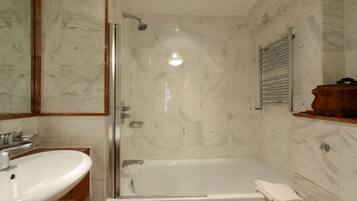A bathroom with a glass-enclosed shower, a sink, and a towel rack.