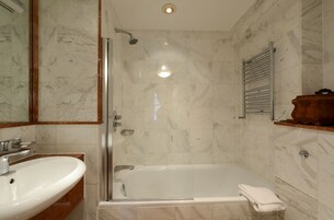 A bathroom with a glass-enclosed shower, a sink, and a towel rack.