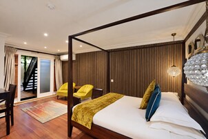 A bedroom with a four-poster bed, a chandelier, and a view of a staircase.