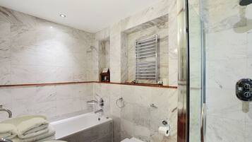 A modern bathroom with a bathtub, toilet, and glass shower enclosure.