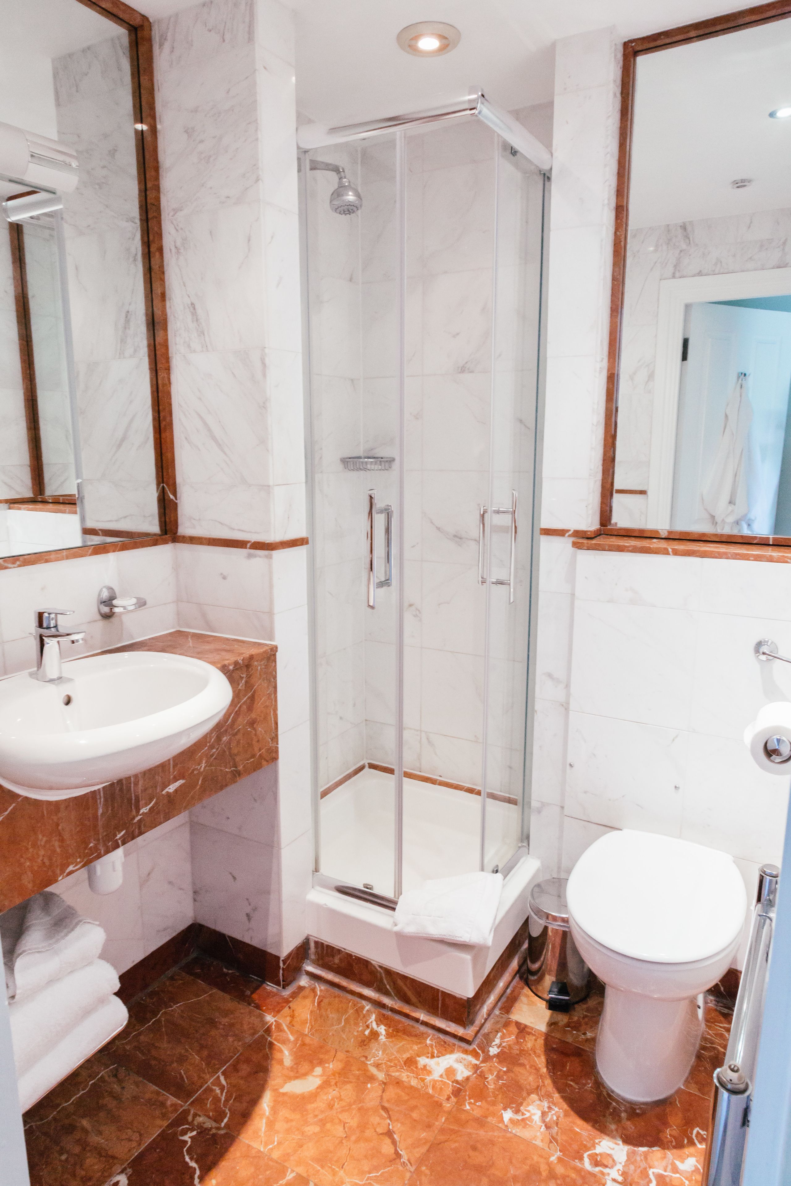 A bathroom with a glass-enclosed shower, a sink, and a toilet.