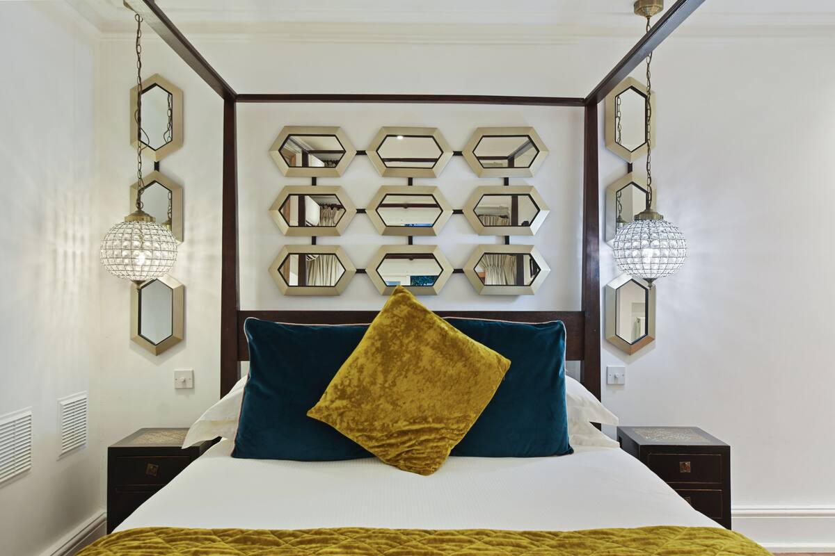 Ein ordentlich eingerichtetes Schlafzimmer mit einem großen Bett, einer Wand voller Spiegel und zwei Nachttischlampen.