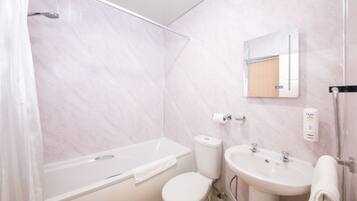 Un baño con bañera, inodoro, lavabo y espejo.